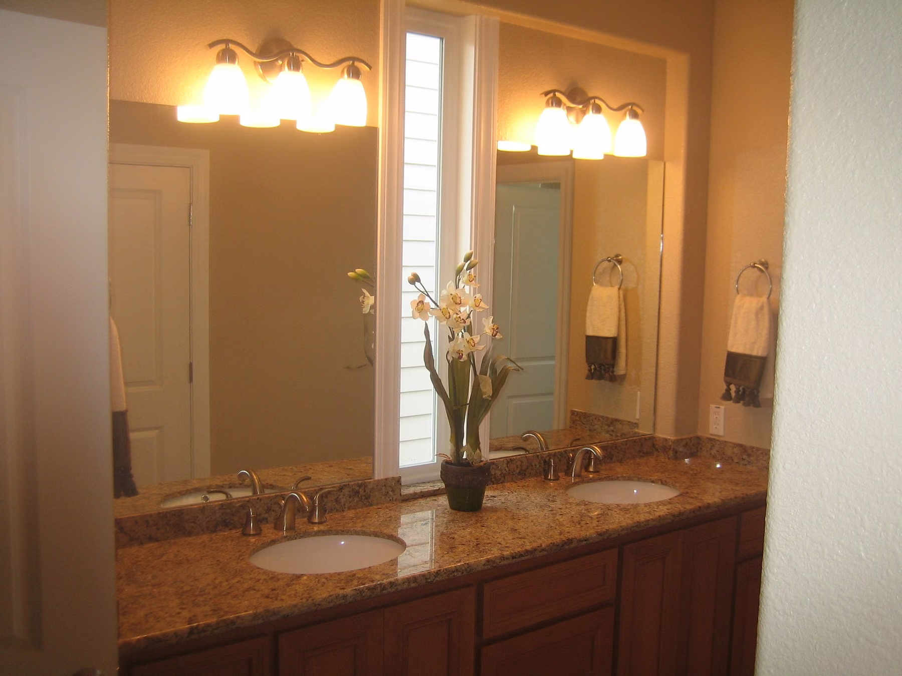 Double vanity with a granite top, twin undermount basins and a wide mirror lit by two bar fixtures