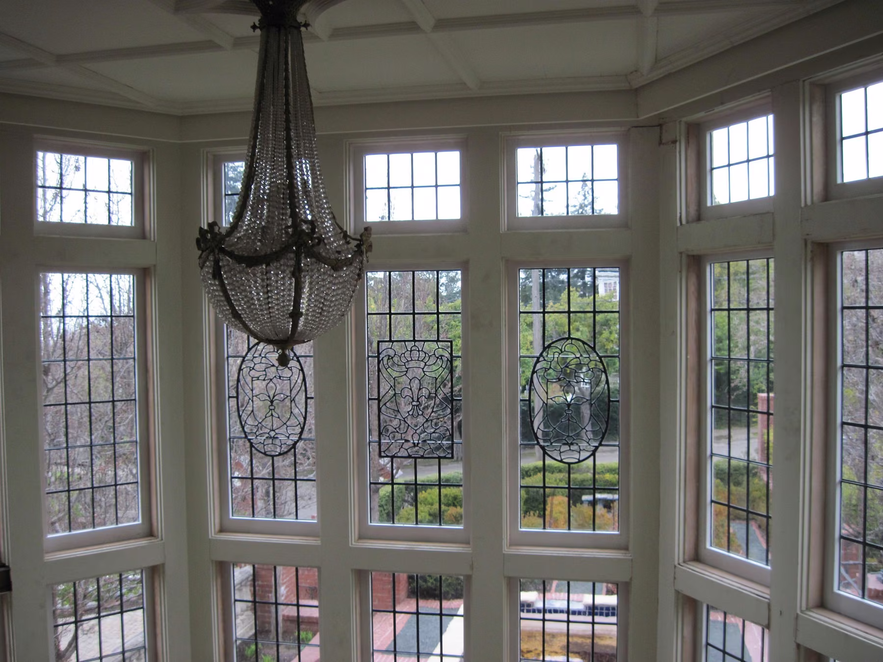 Interior of a leaded-glass window bay with a crystal chandelier and a coffered ceiling