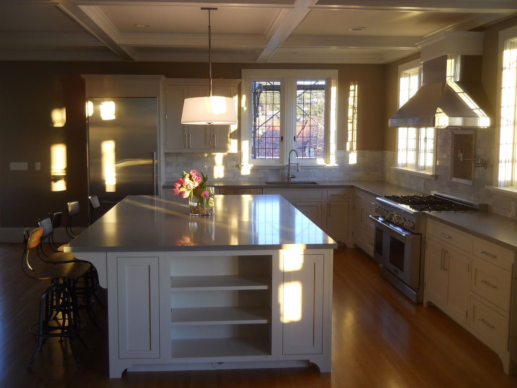 Kitchen rebuilt under a coffered ceiling with a long island, a stainless range and hood and open shelving